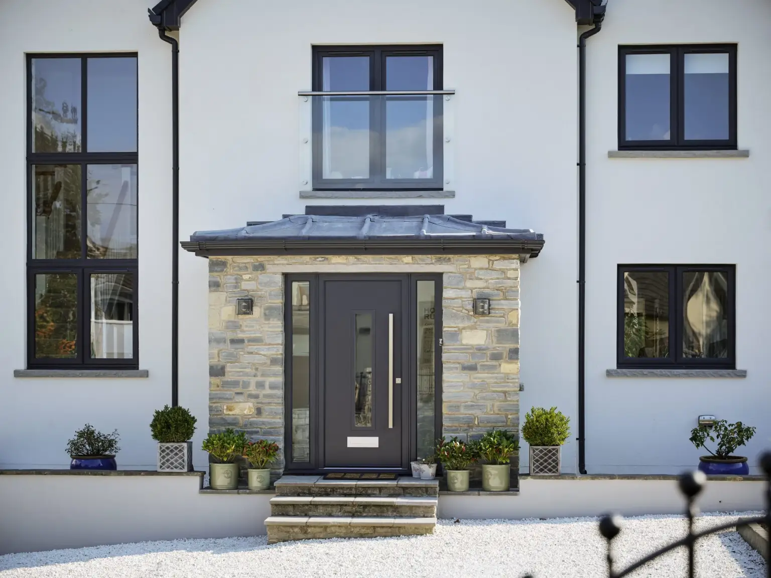 Anthracite grey aluminium entrance door with glazed sidelights in a stone porch