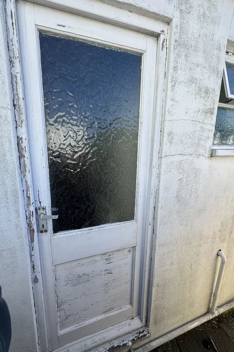 Weathered timber back door with peeling paint and obscure glass before replacement